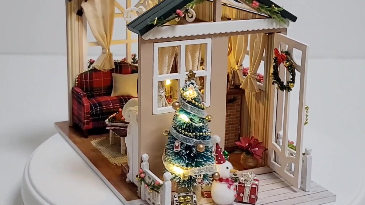 Christmas Cabin miniature with a glowing tree, snowman and gifts on the porch